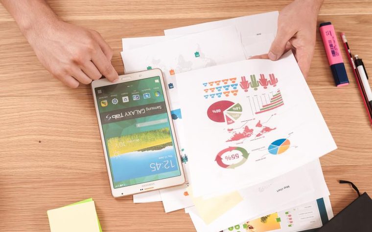 A phone on a desk beside printed charts